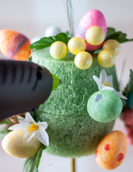 glue being applied to a grean foam pot insert with colourful eggs, leaves, and floral 