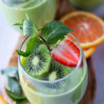 A Cup of Spinach Smoothie garnished with mint, kiwi, and strawberry slices